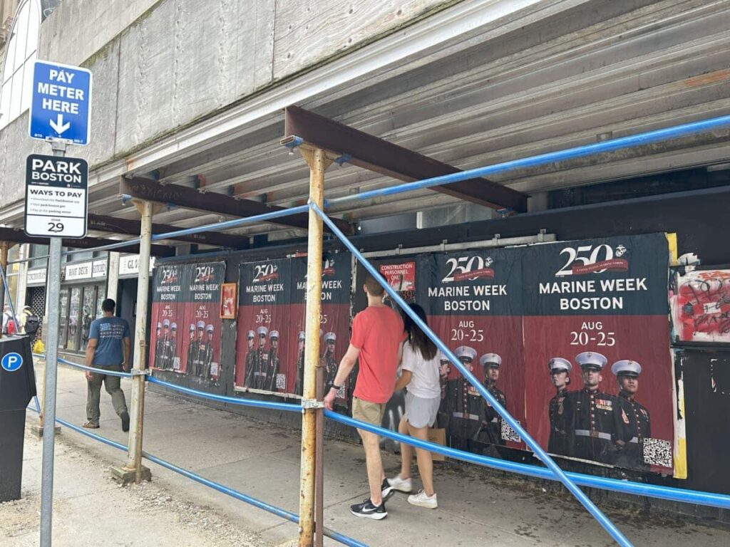 A massive, eye-catching billboard advertisement dominating a busy city street. guerrilla wheatpasting campaigns versus standard billboard advertising