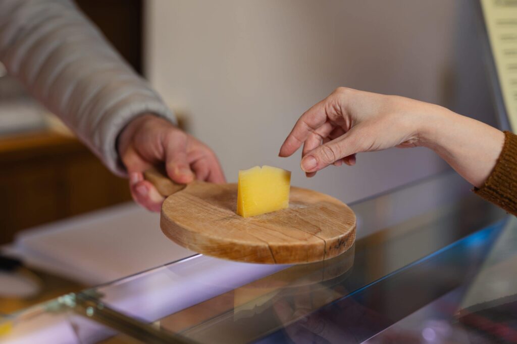 Hand reaching for cheese sample on board.
