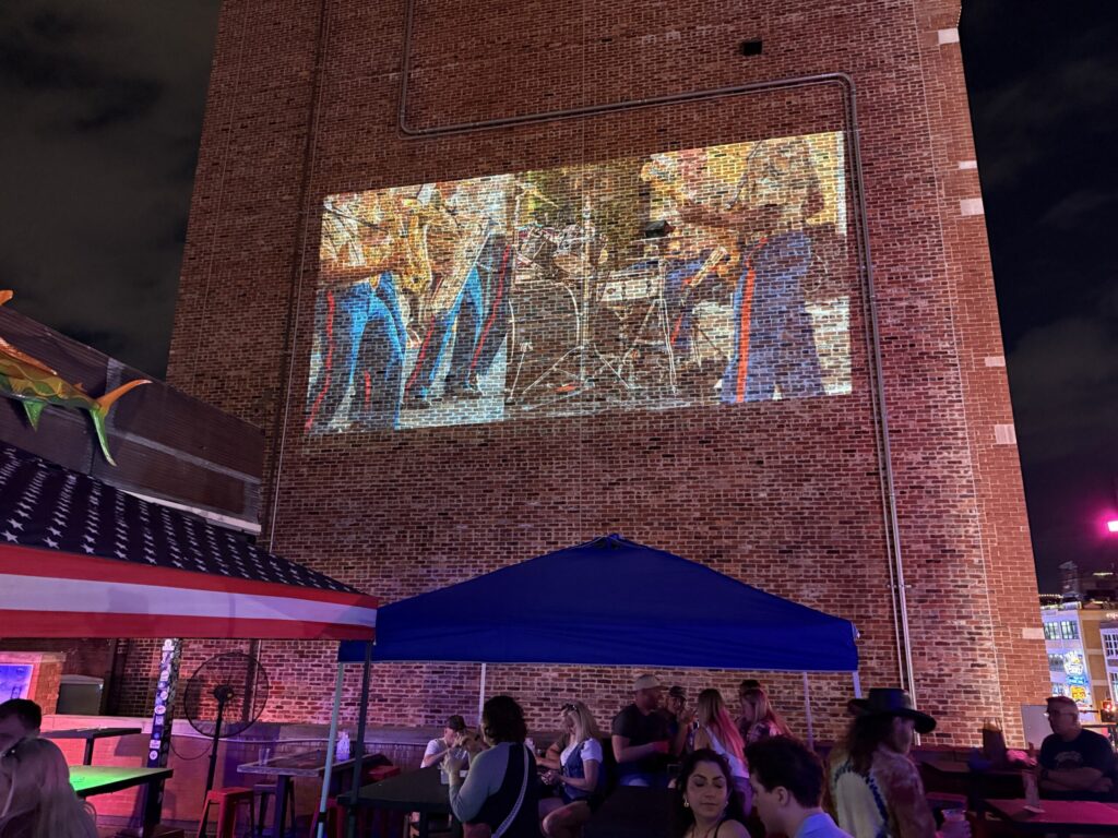 Outdoor gathering with a projected brick mural.