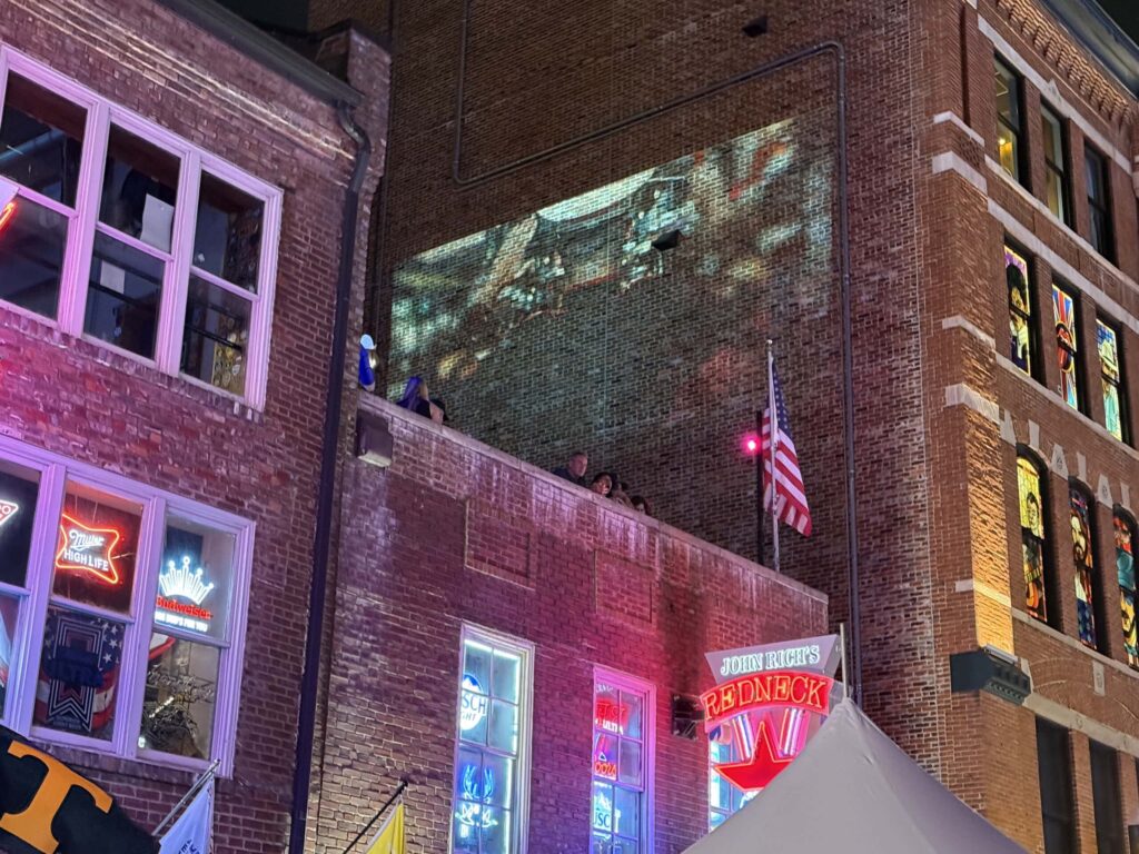 Brick building with neon signs and flag.