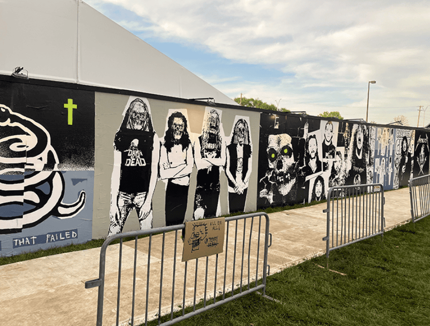 Metallica band mural wallscape at outdoor event venue with crowd control barriers — large-format street advertising by American Guerrilla Marketing