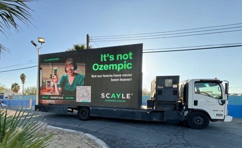 LED billboard truck displaying advertisement with the text "It's not Ozempic But our teams have never been leaner!" and a QR code, showcasing innovative marketing for SCAYLE Commerce Engine.