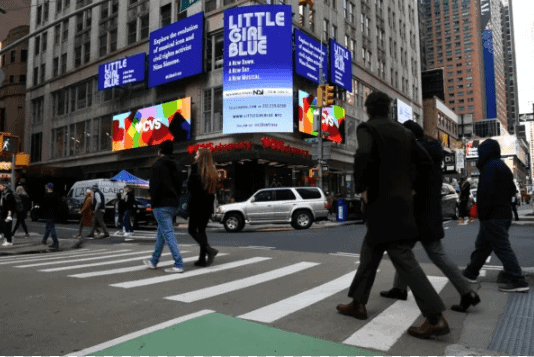 Billboard advertising in a busy urban setting showcasing "Little Girl Blue" musical, with pedestrians crossing the street and vibrant digital displays promoting the show, highlighting the effectiveness of out-of-home (OOH) marketing.