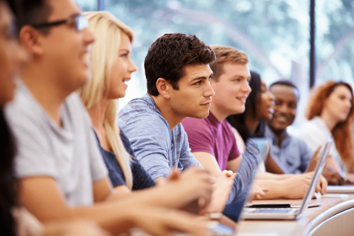 Diverse group of students engaged in a classroom setting, focused on educational opportunities, highlighting the role of advertising in education.