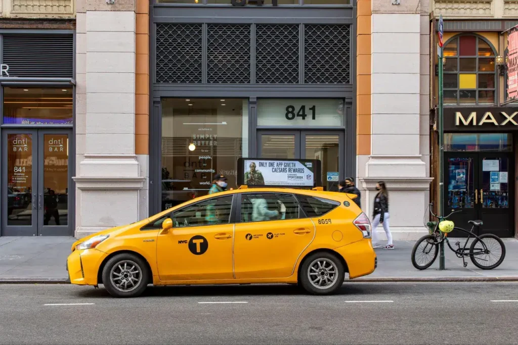 Yellow taxi parked outside a building with the number 841, highlighting urban transportation and advertising opportunities in city environments.