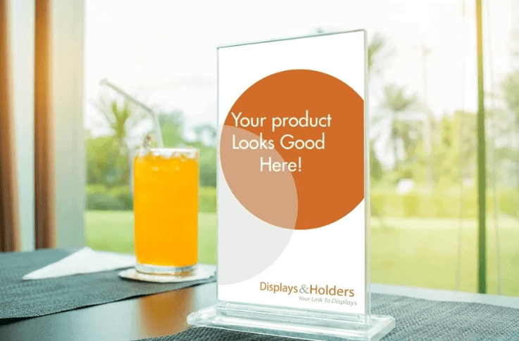 Table top advertising display with promotional message "Your product Looks Good Here!" beside a beverage, emphasizing local business engagement and marketing strategies.