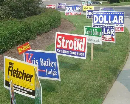 Political campaign yard signs for various candidates, including Donna Stroud, David Miner, Kris Bailey, and Bill Fletcher, displayed in a grassy area, emphasizing local election marketing strategies.