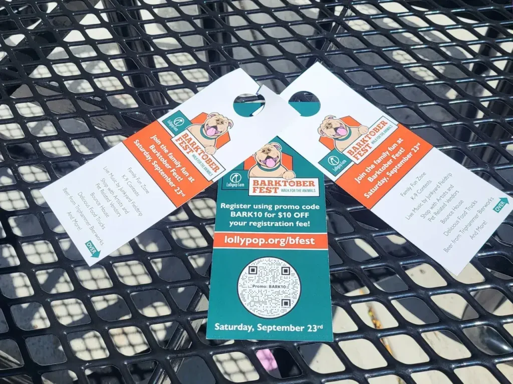 BarkTober Fest promotional door hangers featuring event details and QR code for registration on a table.