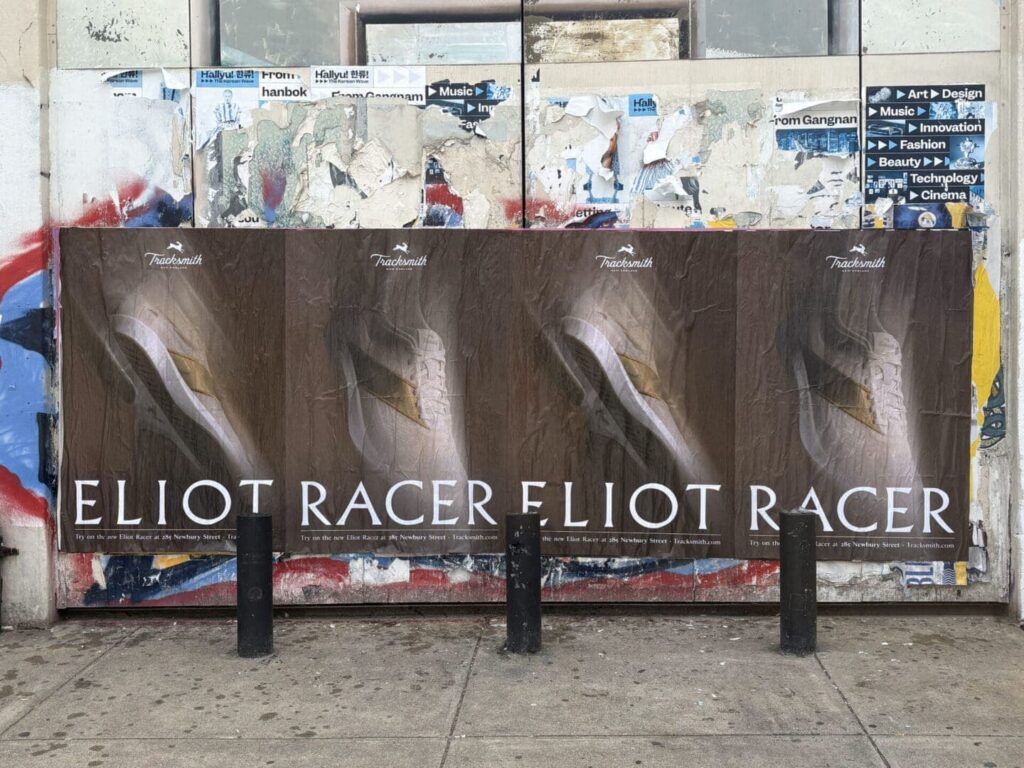 Posters displaying "ELIOT RACER" on a weathered wall, featuring artistic design elements, relevant to guerrilla marketing strategies and advertising techniques.