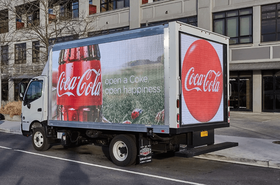 LED billboard truck featuring Coca-Cola advertisement with the slogan "open a Coke, open happiness," parked on a city street, showcasing vibrant branding for outdoor marketing.