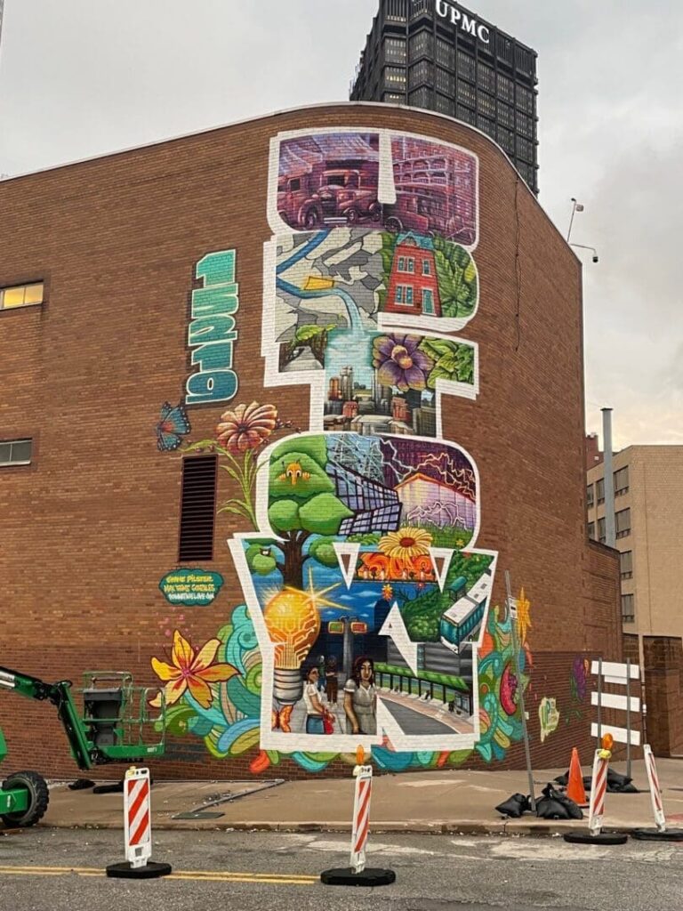 Mural advertising featuring vibrant urban art depicting community themes, nature, and cityscapes, located on a building in New Jersey, relevant to guerrilla marketing strategies.