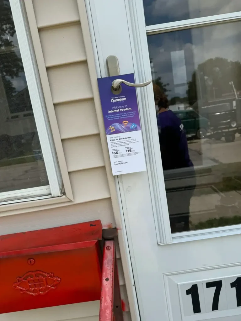 Door hanger advertisement promoting Quantum internet services, featuring pricing details and service highlights, displayed on a residential door.