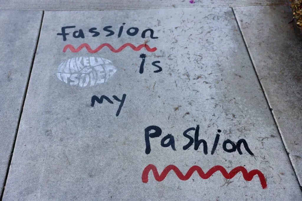 Sidewalk stencil featuring playful text "Fassion is my Pashion" with decorative red wavy lines, highlighting creative street advertising.