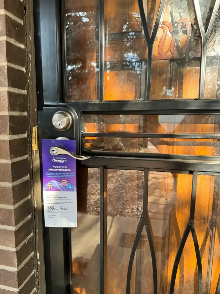 Door hanger advertising for Quantum, featuring a promotional message about "Welcome to Elemental Freedom," displayed on a glass door with a metal handle.