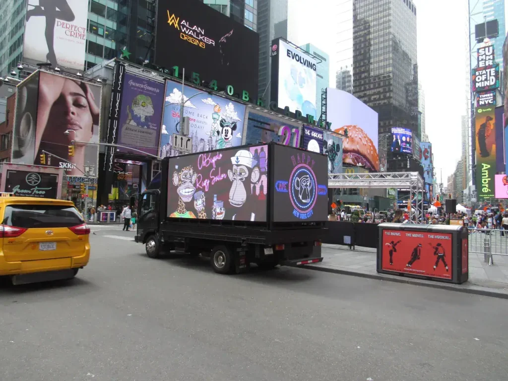 Mobile advertising truck in Times Square displaying colorful promotional graphics, surrounded by vibrant billboards and urban activity, highlighting guerrilla marketing strategies.