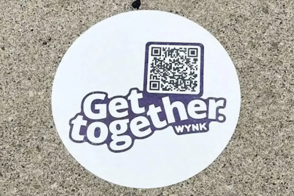 Get together WYNK branded sticker with QR code on a concrete surface, promoting engagement and interaction for brand activation.