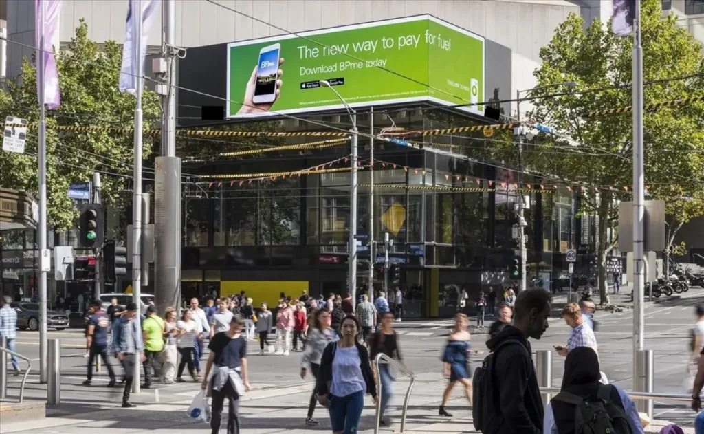 Billboard advertising in a busy urban setting promoting a mobile payment app, with pedestrians walking and engaging in the bustling environment.