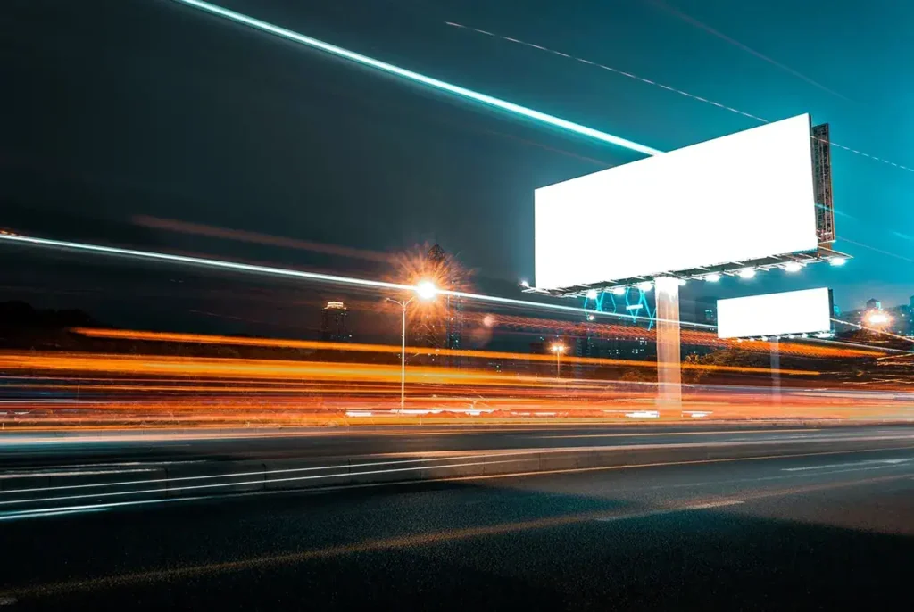Billboard illuminated at night with light trails from passing vehicles, symbolizing the dynamic nature of international marketing and advertising strategies.