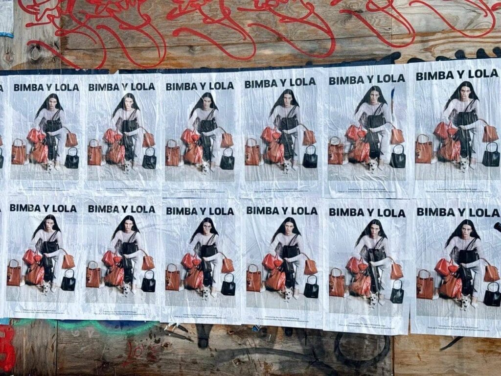 Posters of Bimba y Lola featuring a model with bags, showcasing guerrilla marketing tactics in urban settings.