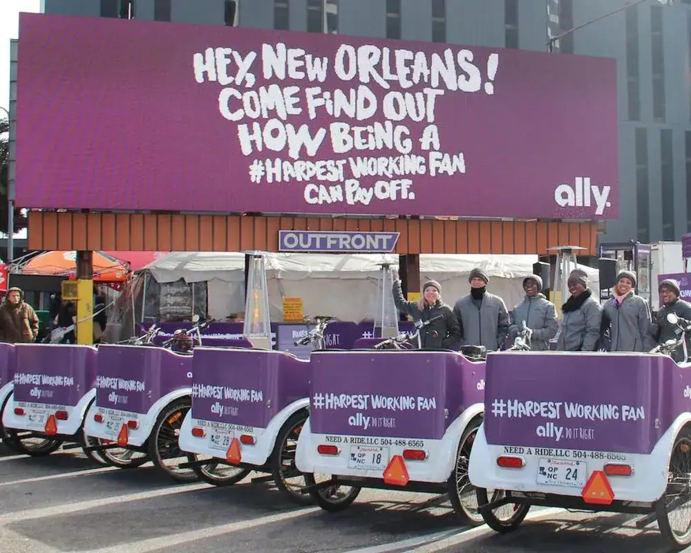 Pedicabs with promotional branding for Ally's "#HardestWorkingFan" campaign, featuring a large billboard targeting New Orleans.