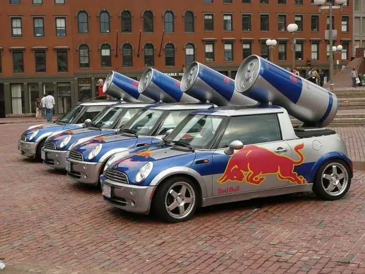 Red Bull-branded Mini Cooper cars with oversized cans on rooftops, showcasing innovative guerrilla marketing strategy in a public space.