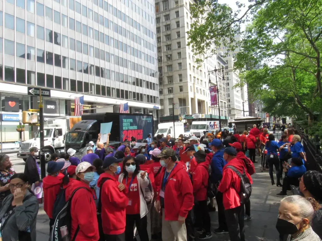 Crowd of people in red jackets participating in a demonstration on a city street, with vehicles and buildings in the background, emphasizing community engagement and public visibility in guerrilla marketing efforts.