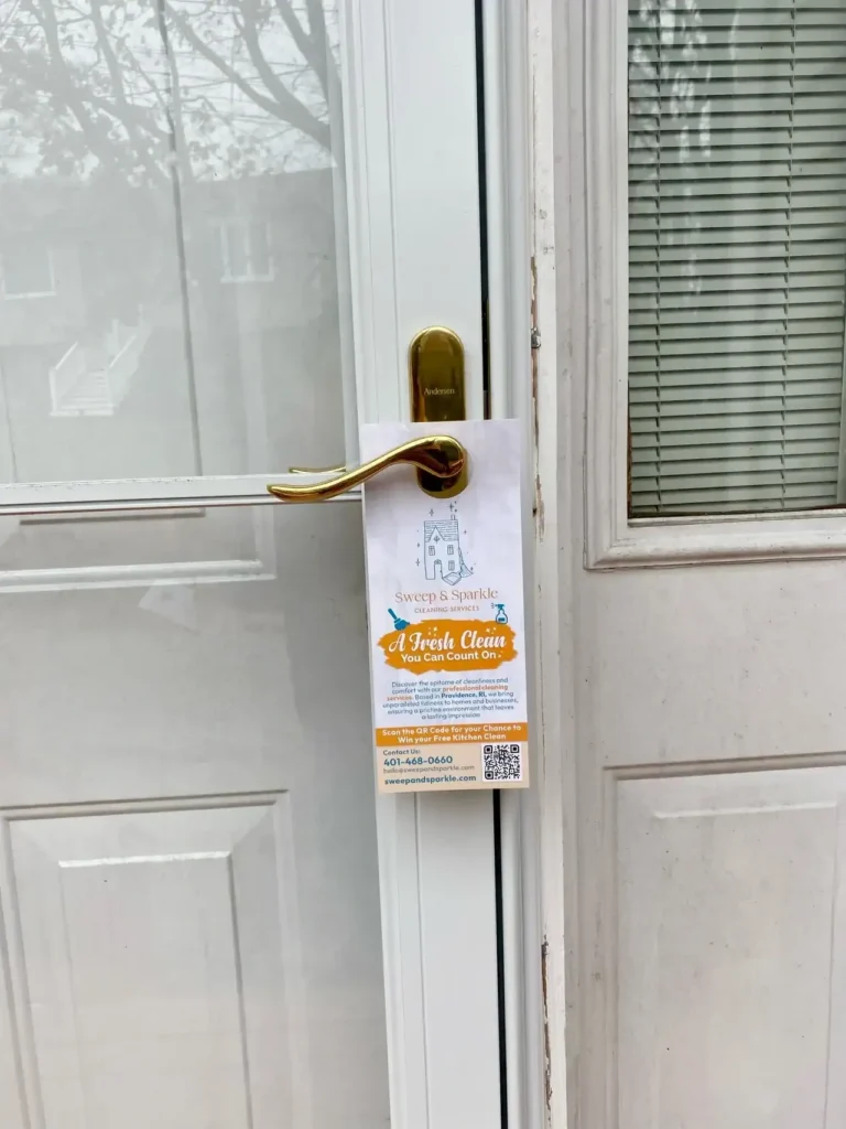 Door hanger advertising cleaning services from "Sweep & Sprinkle" displayed on a residential door, featuring contact information and a QR code for easy access.