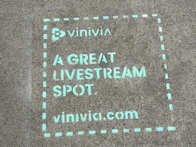 Vinivia promotional mural advertising on pavement, featuring text "A GREAT LIVESTREAM SPOT" and website vinivia.com, highlighting guerrilla marketing strategies.
