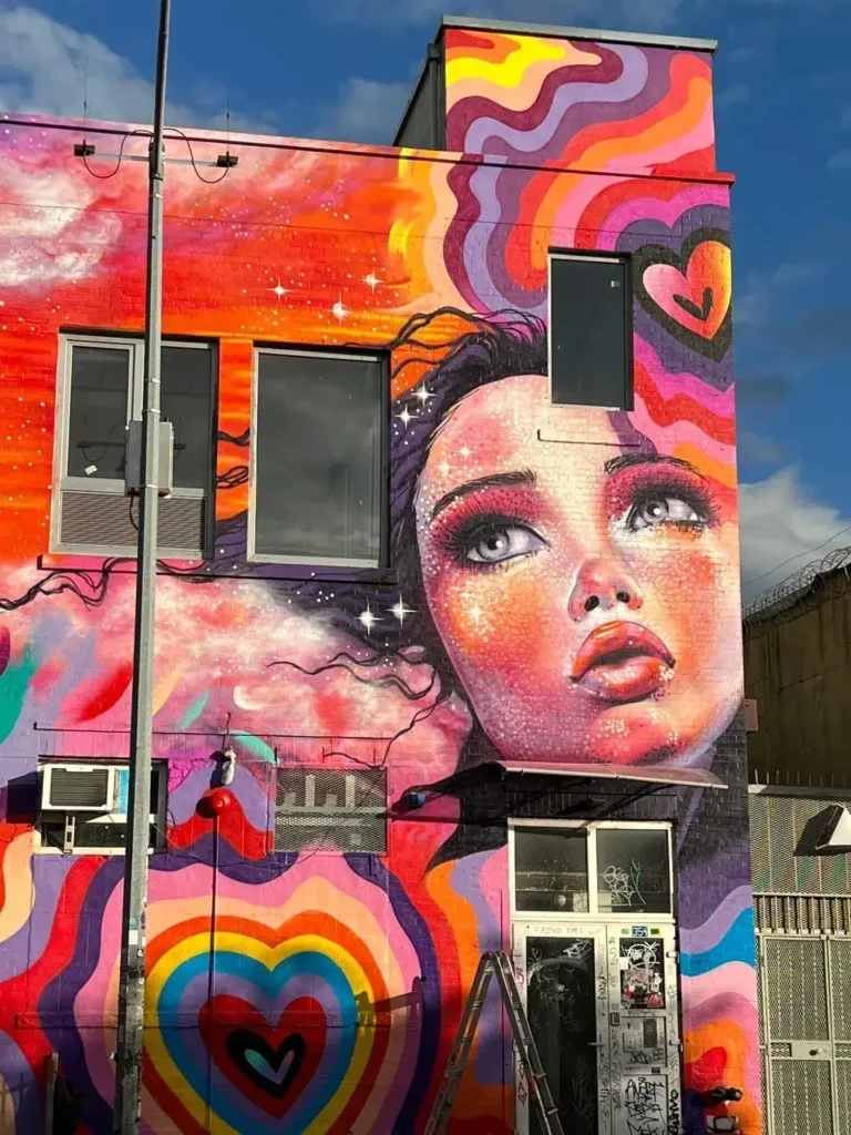 Vibrant mural featuring a woman's face with colorful swirls and hearts, showcasing urban art and street marketing in Idaho.