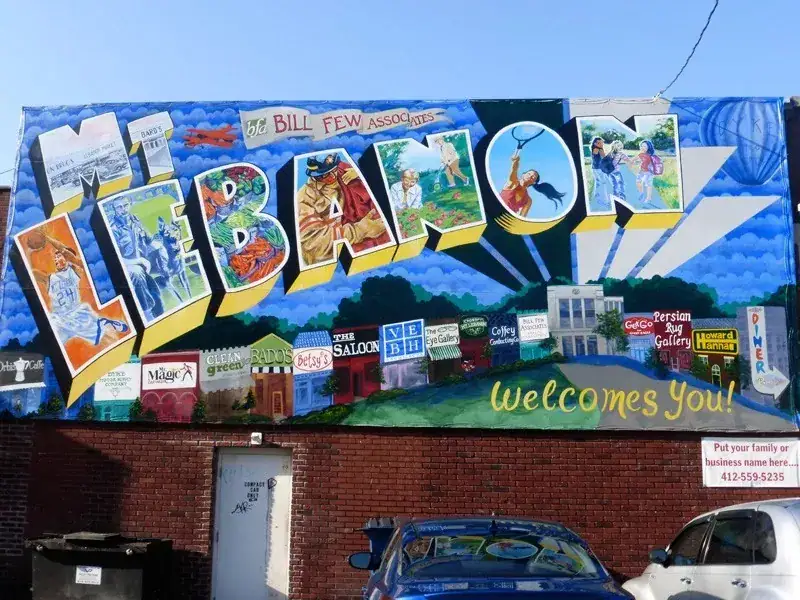 Mural advertising featuring vibrant text "Welcome to Lebanon" with colorful illustrations and local business logos, showcasing guerrilla marketing strategies for urban engagement.