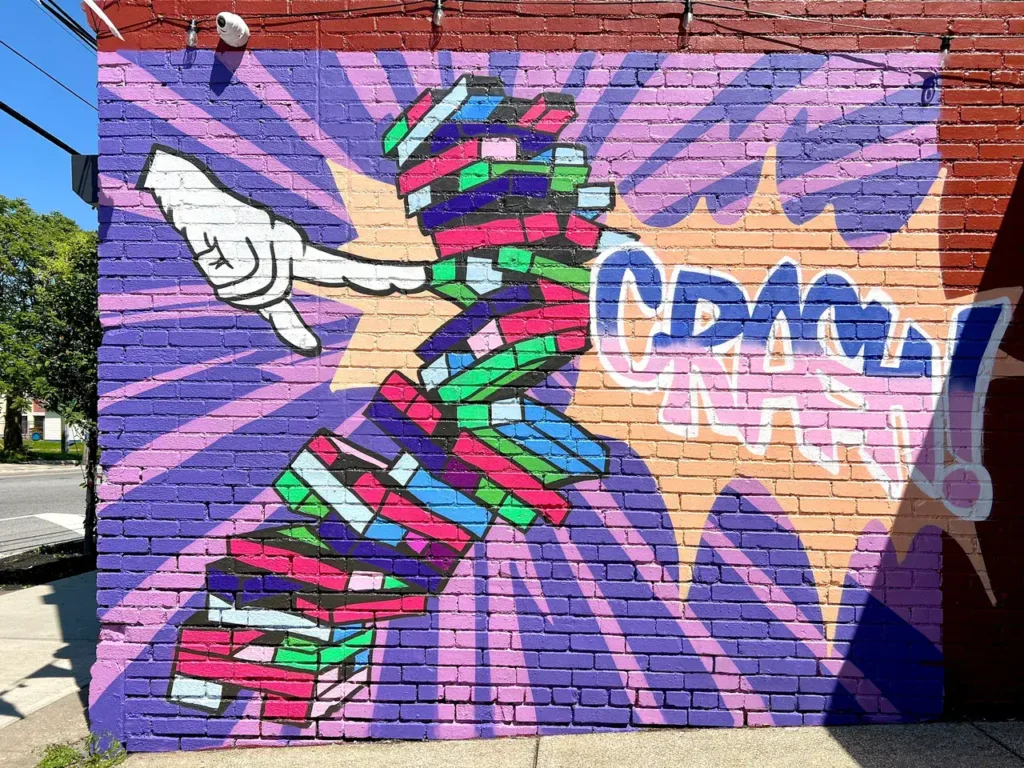 Colorful mural featuring a dynamic hand gesture and the word "CRASH!" against a vibrant background, showcasing guerrilla marketing through street art.