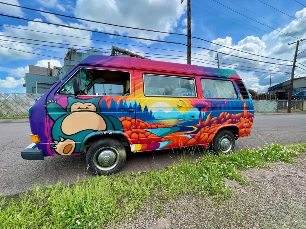 Colorful van with mural featuring a sleeping character and vibrant landscape, representing creative guerrilla marketing tactics in urban settings.