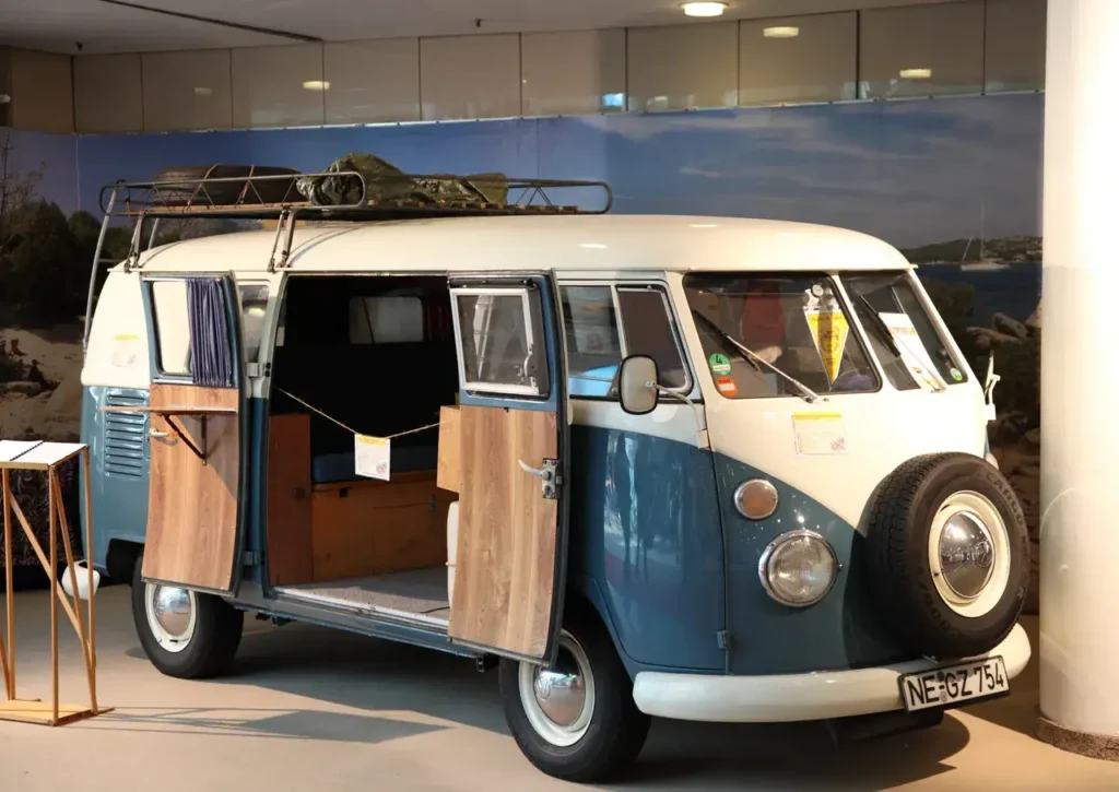 Vintage blue and white Volkswagen van with open doors, showcasing interior space, featured in a marketing context for mobile showrooms and innovative advertising solutions.