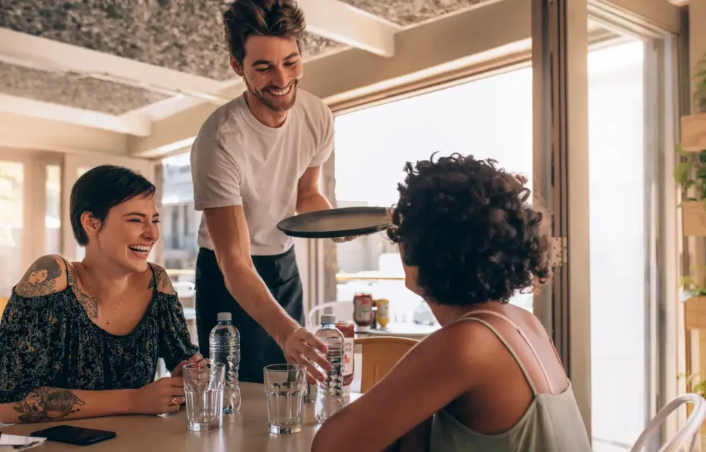 Waitstaff serving food at a dining table, showcasing hospitality and customer engagement in a casual restaurant setting.