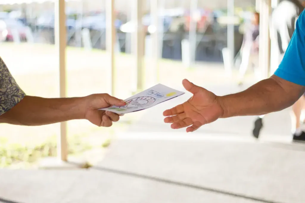 Hands exchanging a flyer, emphasizing flyer distribution in marketing strategies.