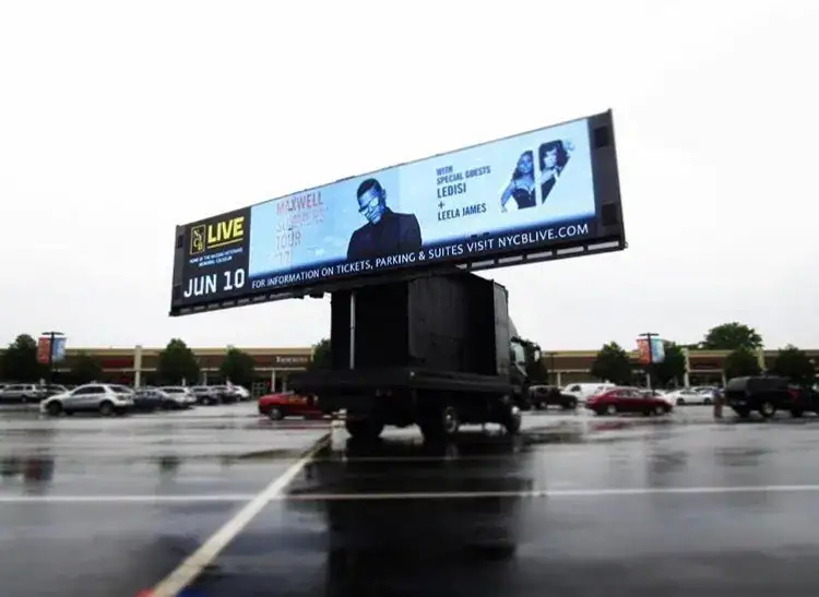 Billboard advertising on a mobile truck promoting an event featuring Maxwell, Leela James, and Ledisi, in a parking lot setting.