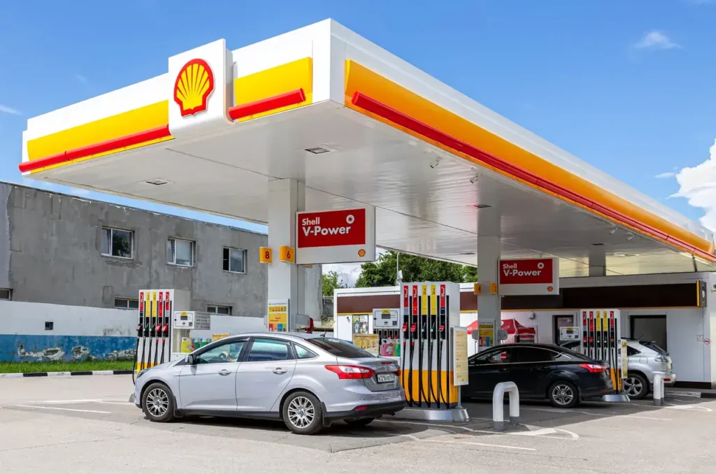 Gas station with Shell branding, featuring fuel pumps and vehicles, illustrating outdoor advertising potential for marketing strategies.
