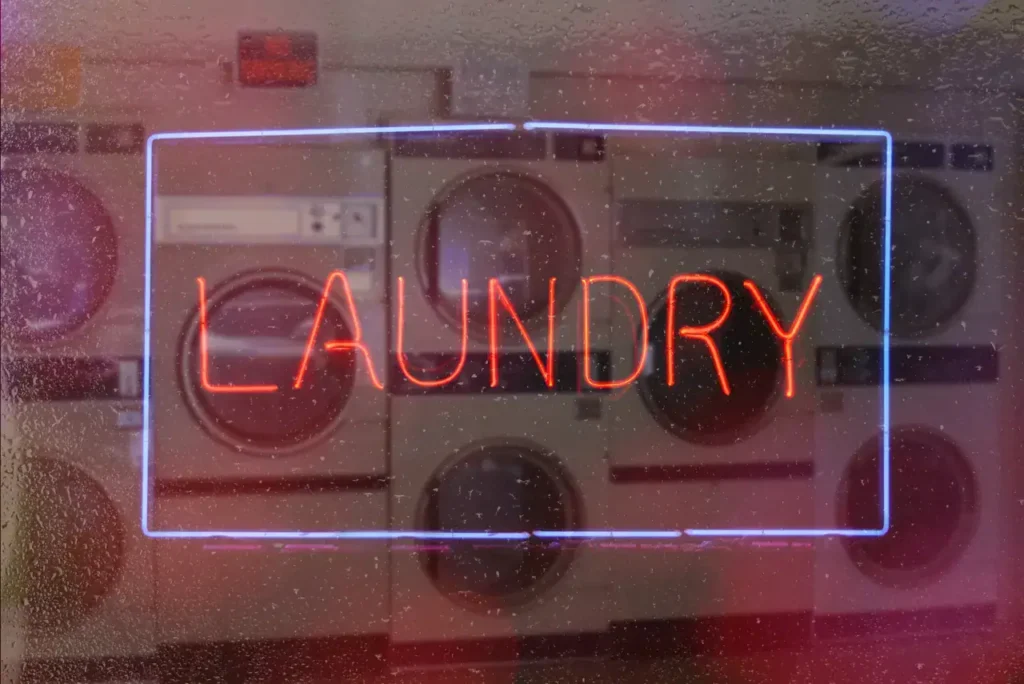Neon sign reading "LAUNDRY" in front of washing machines, emphasizing advertising strategies for laundromats.