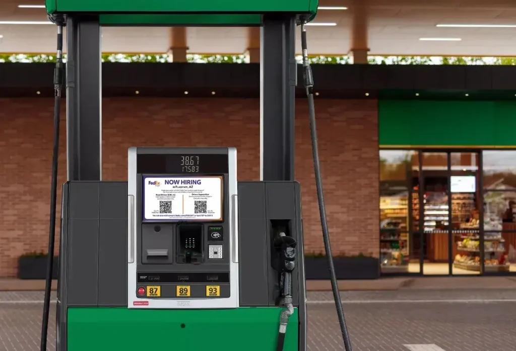 Gas station pump displaying a "NOW HIRING" advertisement for FedEx, showcasing innovative local advertising strategies in a retail environment.