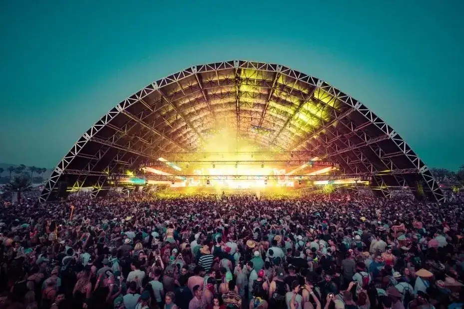 Crowd gathered under a large, illuminated concert venue showcasing a vibrant performance atmosphere, representing event advertising and audience engagement strategies.