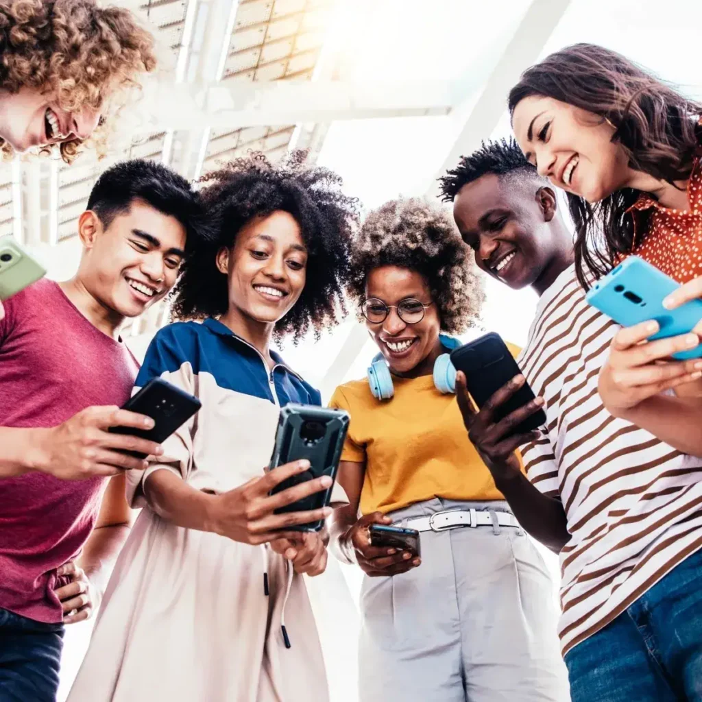 Group of diverse young adults engaging with smartphones, showcasing social interaction and digital connectivity, relevant to modern marketing strategies.