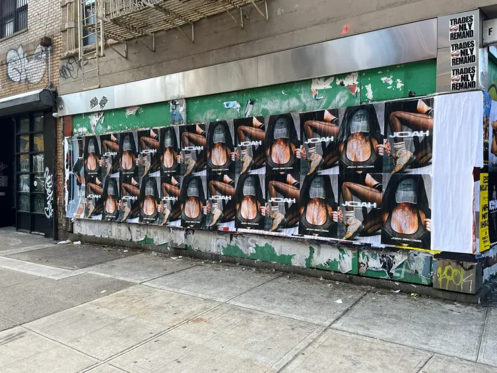 Wall covered with multiple posters featuring a model holding a basketball, promoting the brand "JOAH," in an urban setting, showcasing guerrilla marketing techniques for brand visibility.