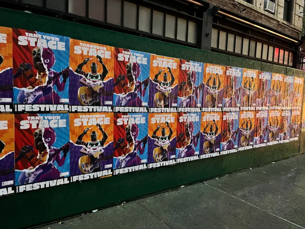 Colorful posters promoting a festival, featuring bold graphics and the phrase "Take Your Stage," displayed on a wall, representing urban advertising strategies relevant to guerrilla marketing campaigns.