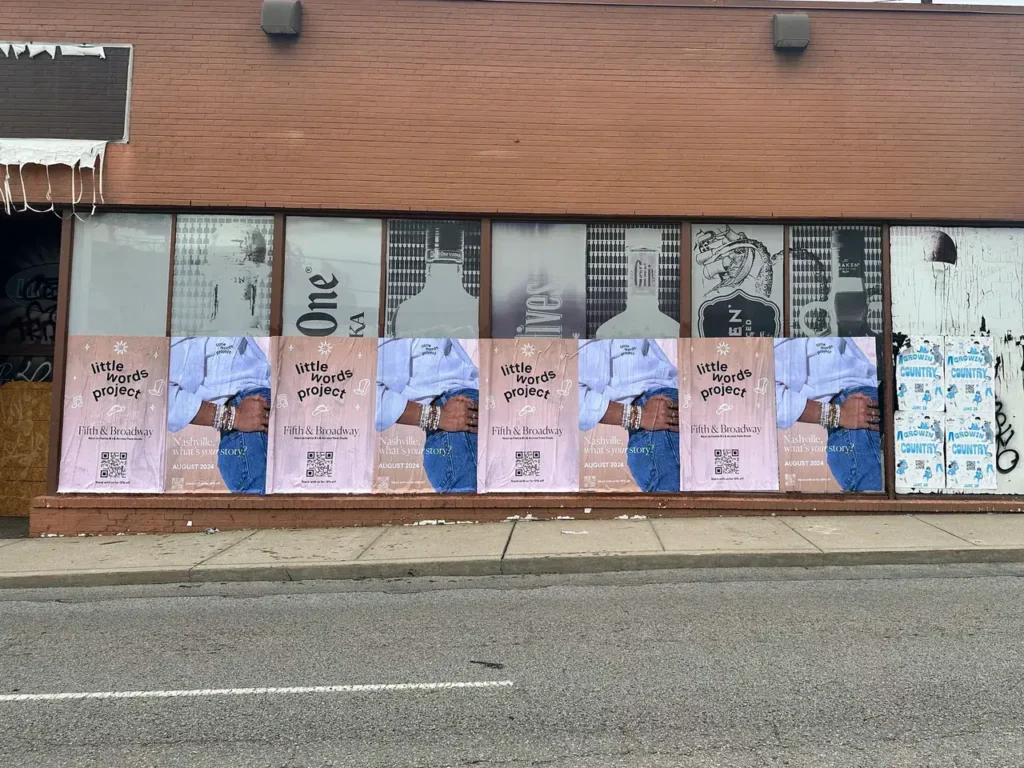 Posters featuring "little words project" displayed on a storefront, showcasing a creative advertising strategy for brand visibility in urban environments.