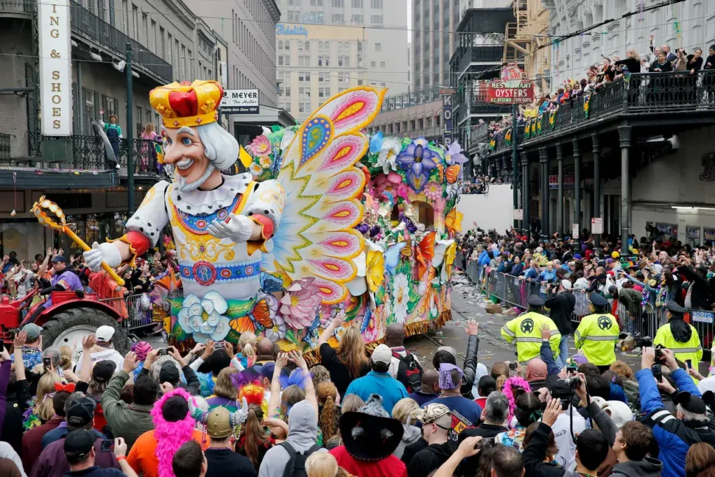 Mardi Gras parade float featuring a king figure with a colorful butterfly design, surrounded by a large crowd of spectators celebrating the event.