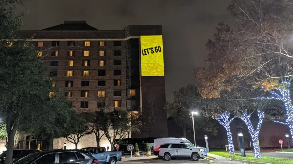 Hotel building illuminated at night with a large projection displaying the text "LET'S GO," showcasing guerrilla projection advertising techniques.