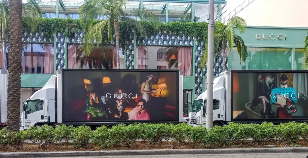 Gucci billboard on trucks outside store.