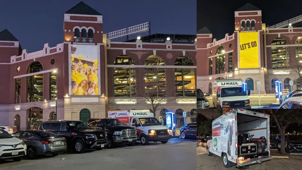 U-Haul trucks parked near a stadium featuring large advertising banners, including a "LET'S GO" message, highlighting street advertising and guerrilla marketing strategies.