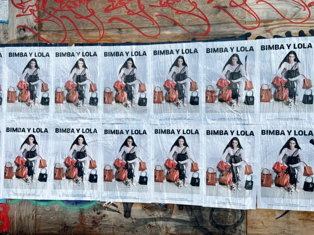 Bimba y Lola promotional posters featuring a model with bags, displayed on a textured surface with graffiti, emphasizing guerrilla marketing strategies.
