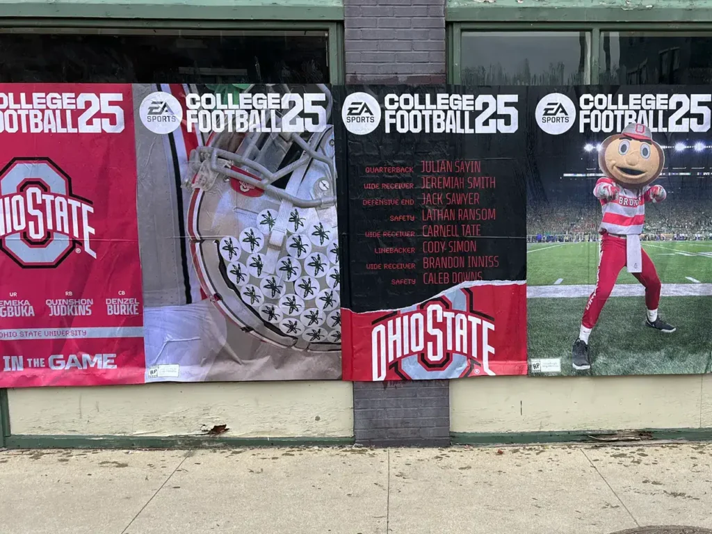 Banners featuring Ohio State football players and mascot, promoting EA Sports College Football 25, displayed in a storefront window.
